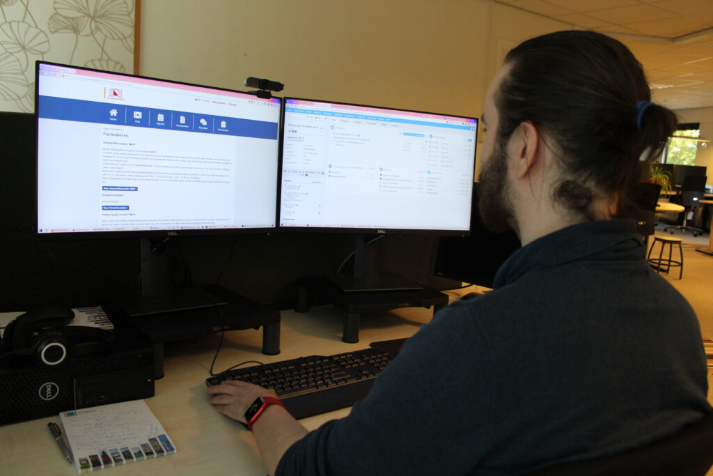 Medewerker kijkt naar zijn monitor met de ZorgNed-applicatie.